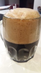 Homemade dark beer with foam.